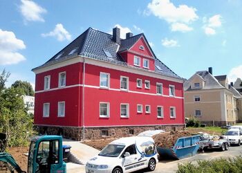fertig saniertes Haus mit Baufahrzeugen davor